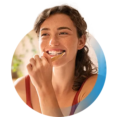 Frau lächelt beim Zähne putzen mit Zahnzusatzversicherung vom Testsieger