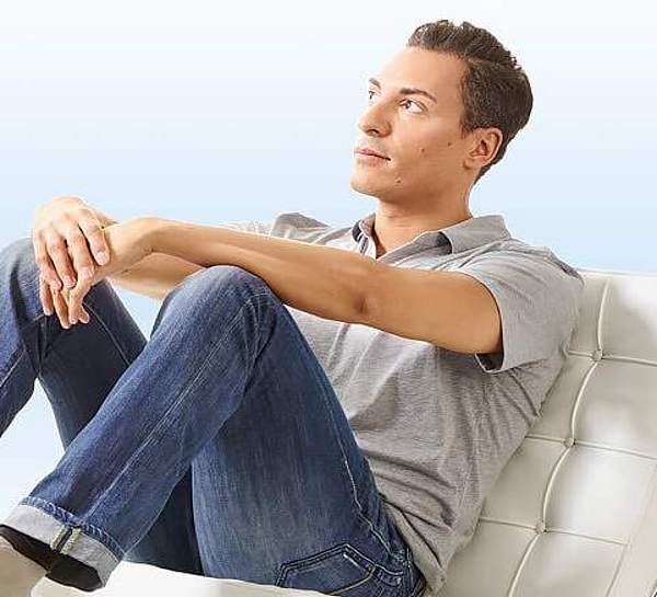 Junger Mann sitzt nachdenklich auf einem Sessel - Münchener Verein Krebszusatzversicherung