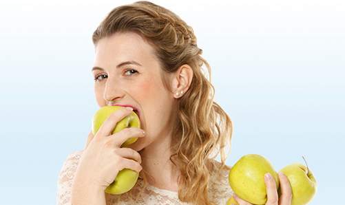 Zahnzusatzversicherung Münchener Verein - Junge Frau beißt in einen Apfel