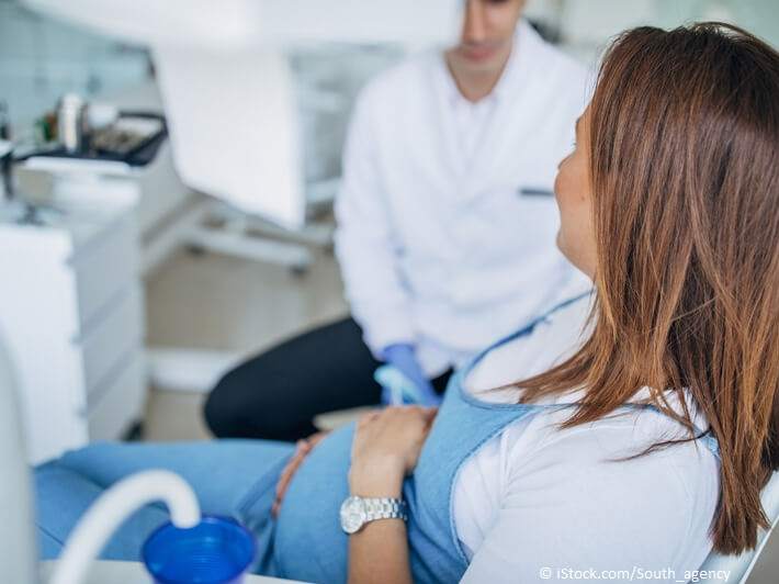 Zahnbehandlung in der Schwangerschaft: Junge Schwangere im Gespräch mit ihrem Zahnarzt
