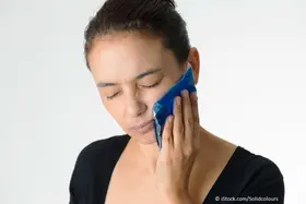 Kälte gegen Zahnschmerzen -  jungen Frau, die Eisbeutel auf ihr Gesicht hält