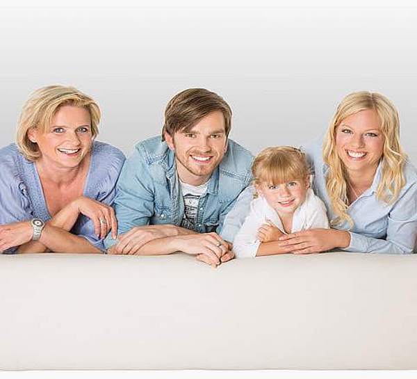 Familie liegt auf Sofa und lächelt - Münchener Verein Zahnzusatzversicherung