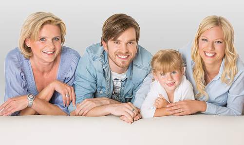 Familie liegt auf Sofa und lächelt - Münchener Verein Zahnzusatzversicherung