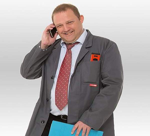 Ein Handwerksmeister telefoniert mit seinem Handy und lächelt - Münchener Verein Gruppenunfall-Versicherung