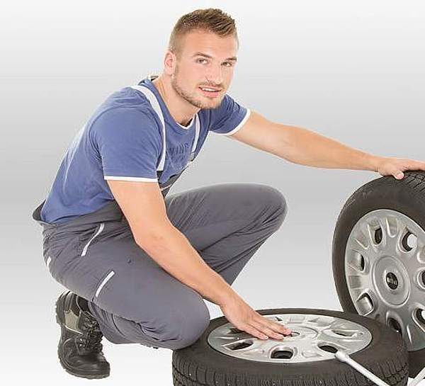 Junger Mann beim Reifenwechsel - Kfz-Versicherung vom Münchener Verein