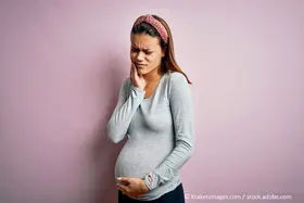 Zahnschmerzen in der Schwangerschaft_Junge, schwangere Frau mit schmerzverzerrtem Gesicht hält sich die Wange