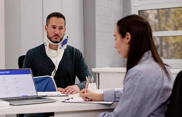 Bild eines Mannes, der mit Halskrause einen Termin bei einer Versicherungsberaterin wahrnimmt.