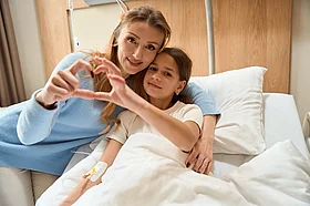 Bild einer Frau und ihrer Tochter, die in einem Krankenhausbett liegt.