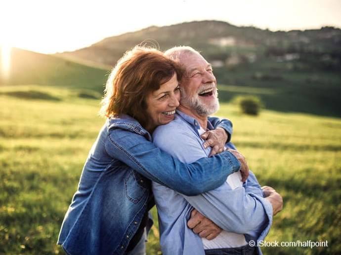 Patientenverfügung und Betreuungsvollmacht_Glückliches älteres Paar umarmt sich draußen in der Natur bei Sonnenuntergang