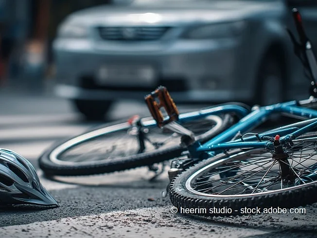 Bild eines am Boden liegenden Fahrrads vor einem Auto.