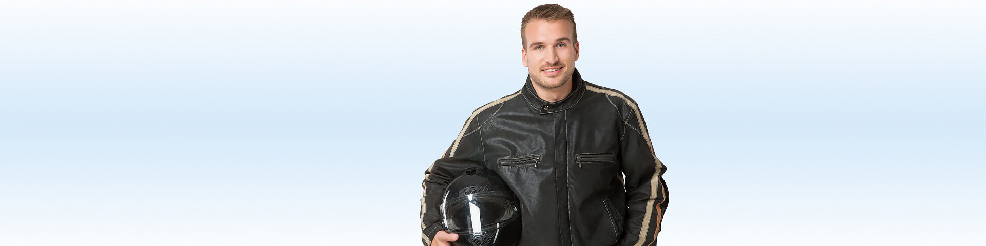 Ein junger Motorradfahrer hält seinen Helm im unter dem Arm - Münchener Verein Kfz-Versicherung