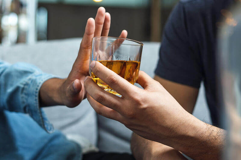 Alkohol schwächst die Abwehrkräfte – eine Person verweigert  Alkohol durch ein Handzeichen.