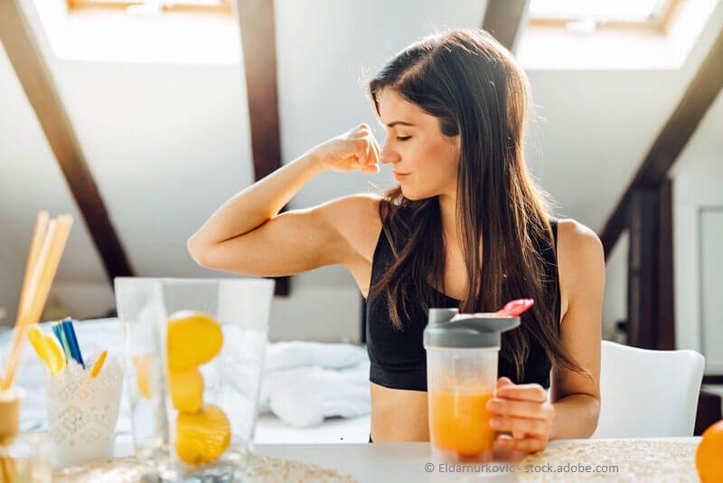Starkes Immunsystem - Junge, sportliche Frau trinkt einen frischgepressten Orangensaft 