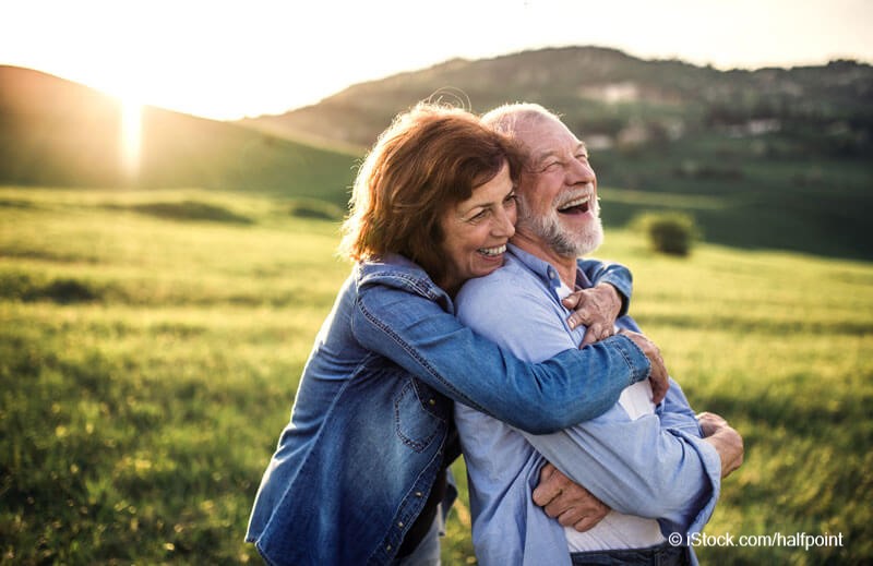Patientenverfügung und Betreuungsvollmacht_Glückliches älteres Paar umarmt sich draußen in der Natur bei Sonnenuntergang