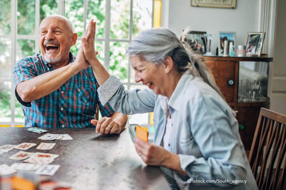 Wohnenformen im Alter - ältere Menschen spielen gemeinsam Karten Im Seniorenheim