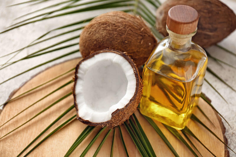 Arrangement mit einer Kokosnuss  und Kokosnussöl auf einem Holzbrett.