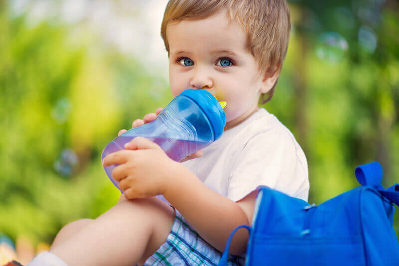 Süßer kleiner Junge trinkt Wasser aus einer Babytrinkflasche.