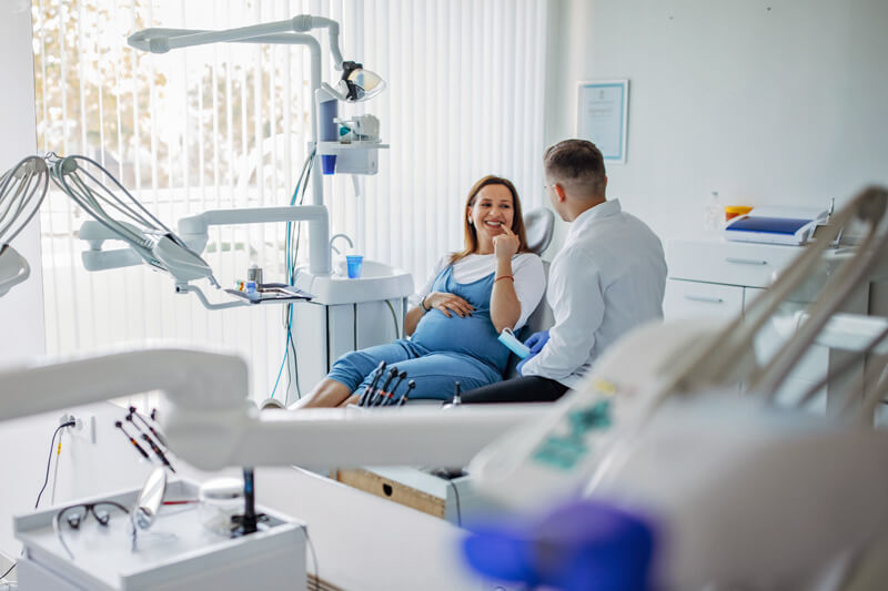 Schwangere Frau in einer Beratungssituation beim Zahnarzt - Ratgeber Zahngesundheit - Münchener Verein