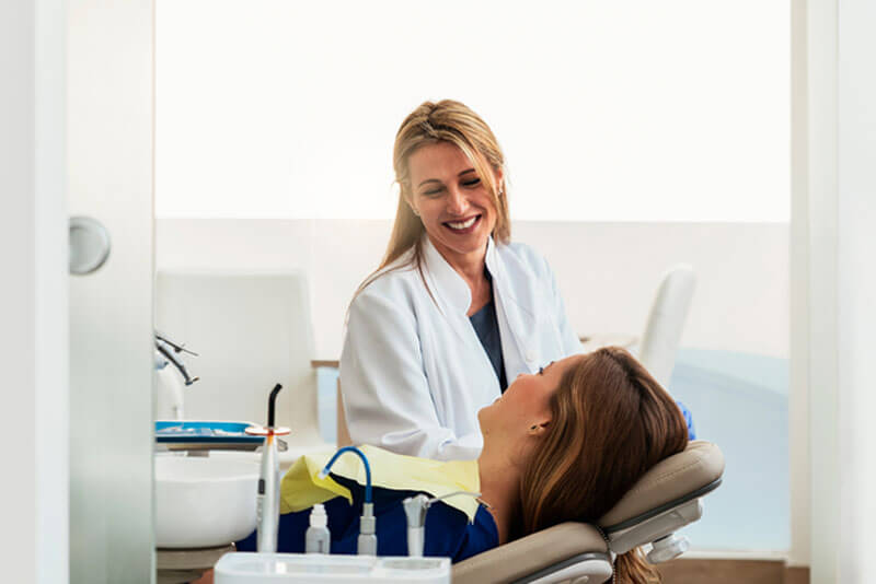 Professionelle Zahnreinigung_Lächelnde Zahnärztin während einer Behandlung bei einer Patientin.