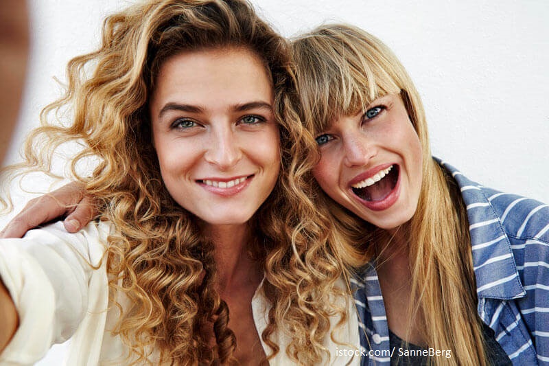 Zahnversicherung sinnvoll? Zwei Freundinnen mit strahlendem Lächeln machen ein Selfie.