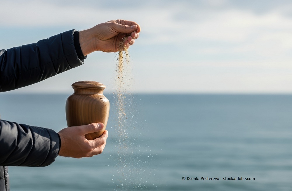 Bild einer Urne, aus der Asche &uuml;ber dem Meer verteilt wird.
